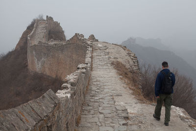 Rear view of man walking on great wall of china in foggy weather