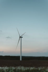 Windmill on field against sky during sunset