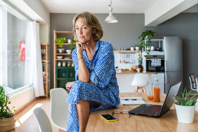 Portrait of young woman using phone while sitting at home