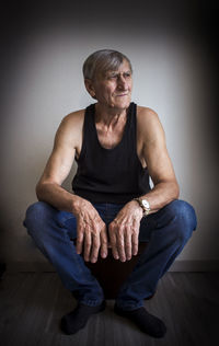 Portrait of man sitting against wall