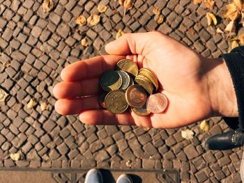 Low section of person with coins standing on street during sunny day