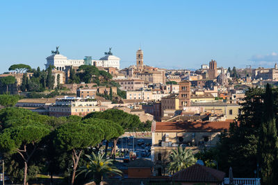 Buildings in city against clear blue sky