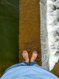 Low section of man standing by water