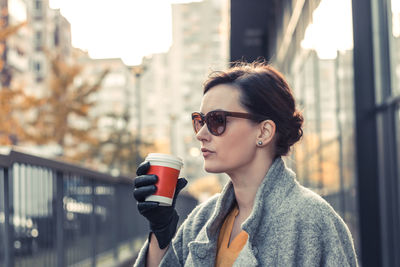 Close-up of woman having coffee while standing in city