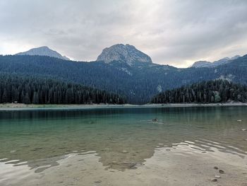 Scenic view of lake by mountains against sky