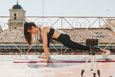 Young sporty fit woman coach doing online lessons through video call on her mobile phone streaming