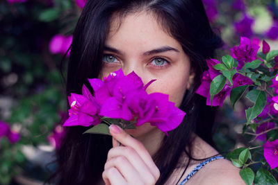 Close-up portrait of beautiful woman holding purple flowers