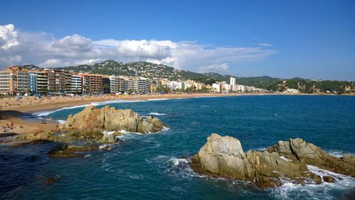 Scenic view of sea by buildings against sky on sunny day