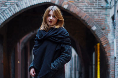 Portrait of young woman standing against arch