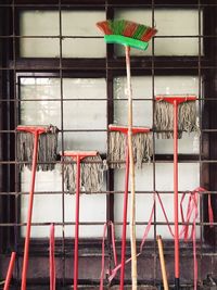 Mops and broom at metal grate of closed window