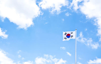 Low angle view of flag waving against sky