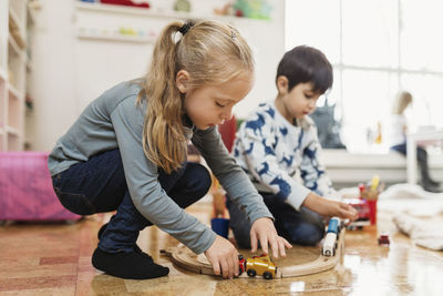 Boy and girl playing with toy train at preschool