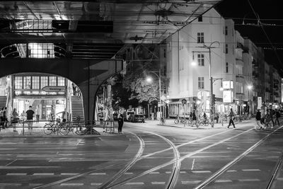 People walking on street with railroad tracks at night