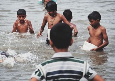 Rear view of shirtless boy in water