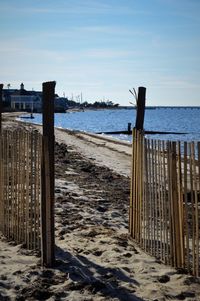 Wooden posts on beach against sky