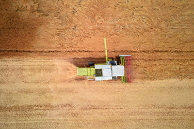 Aerial view of working harvesting combine in wheat field, harvest season