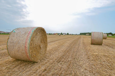 Hay bales on field against sky