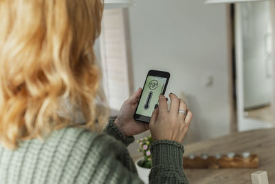 Woman adjusting temperature on smart phone at home