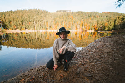 Man sitting by lake against trees