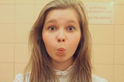 Close-up portrait of woman puckering against wall