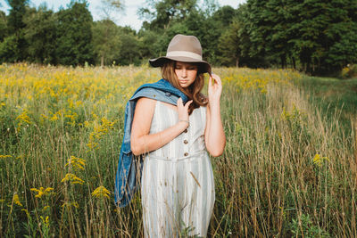 Teen girl wearing a hat standing in a field of goldenrod