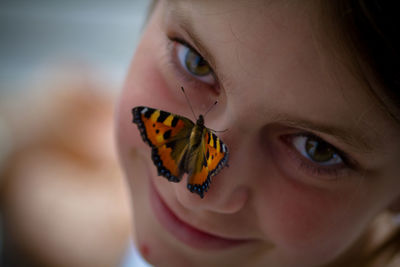 Close-up portrait of girl with butterfly on nose