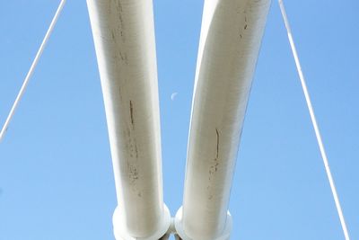 Low angle view of poles against clear blue sky