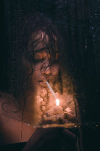 Close-up of woman holding burning candle