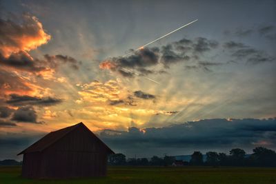 House on field against sky at sunset