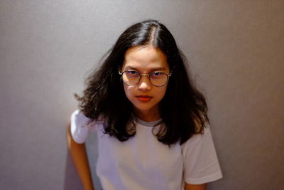 Portrait of a beautiful young woman standing against wall