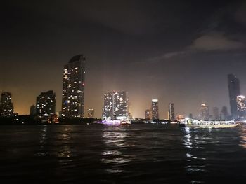 Illuminated buildings in city against sky at night