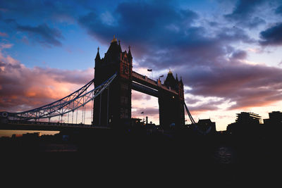 Silhouette tower bridge against cloudy sky