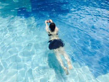 High angle view of woman swimming in pool on sunny day