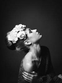 Close-up of woman with roses against black background