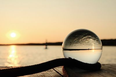 Close-up of crystal ball on water against clear sky during sunset