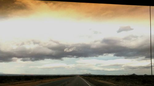 Country road against cloudy sky