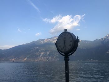 Clock on lake against mountain range