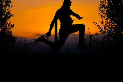 Silhouette person standing by tree against sky during sunset