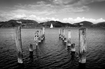 Wooden posts in sea against sky