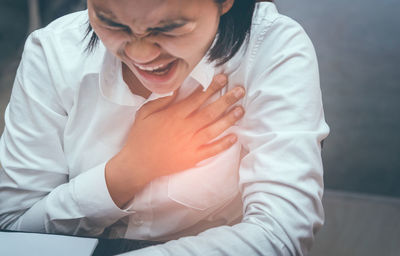 Woman having chest pain sitting at table 
