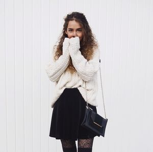 Portrait of young woman standing against white wall