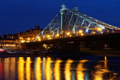 Illuminated bridge over river against sky at night