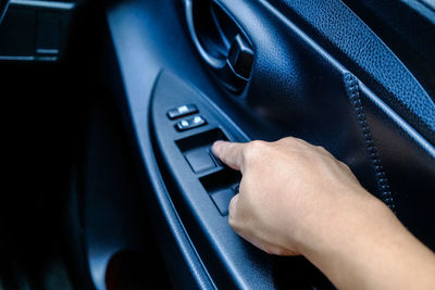 Cropped hand touching push button on car door