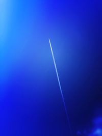 Low angle view of vapor trails in blue sky