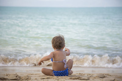 Adorable toddler girl playing on sandy beach of tropical island