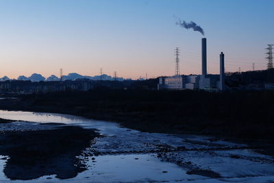 Smoke emitting from factory against sky during winter