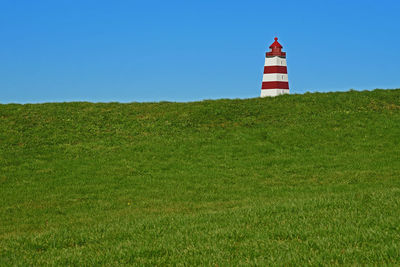 Lighthouse on field against sky