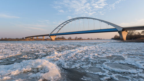 Bridge over river against sky during winter