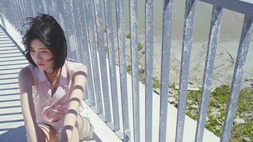 Young woman on railing against trees