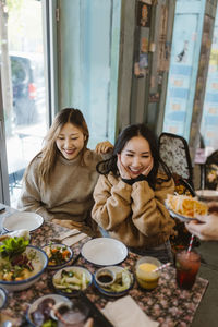 Happy female friends sitting together at restaurant